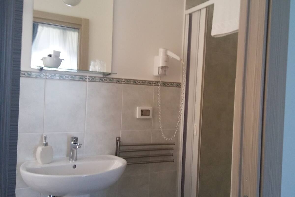 Un baño con lavabo, espejo, toallero y zona de ducha.