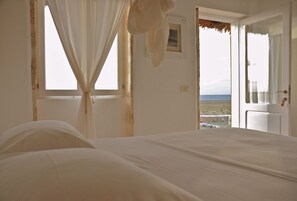 Une chambre avec un lit, une fenêtre avec des rideaux et une vue sur la plage.