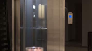 An elevator interior with a glass door, a digital display, and a control panel.