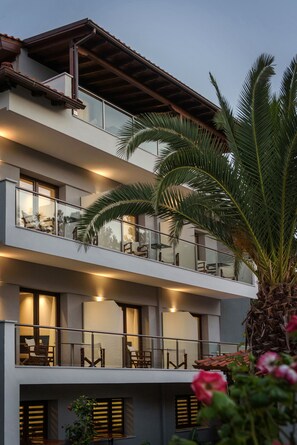 A multi-story hotel with balconies, large windows, and a palm tree.