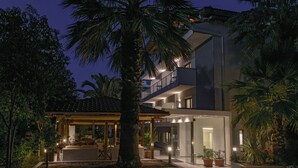 Uma casa moderna de dois andares com varanda coberta, janelas amplas e entrada bem iluminada.