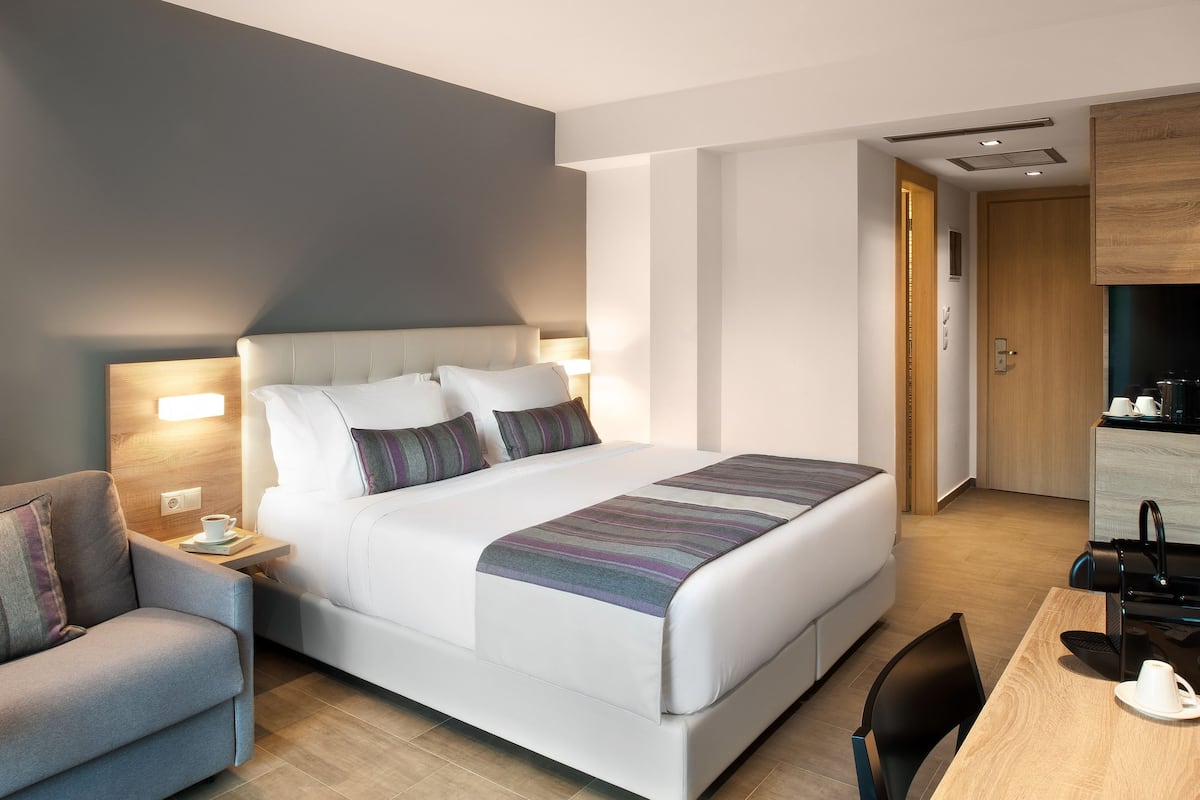 Een moderne hotelkamer met een groot bed, nachtkastjes, een bureau en een stoel.
