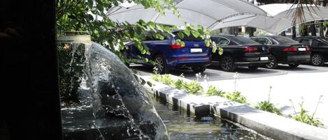 A parking area with cars and a small water feature.