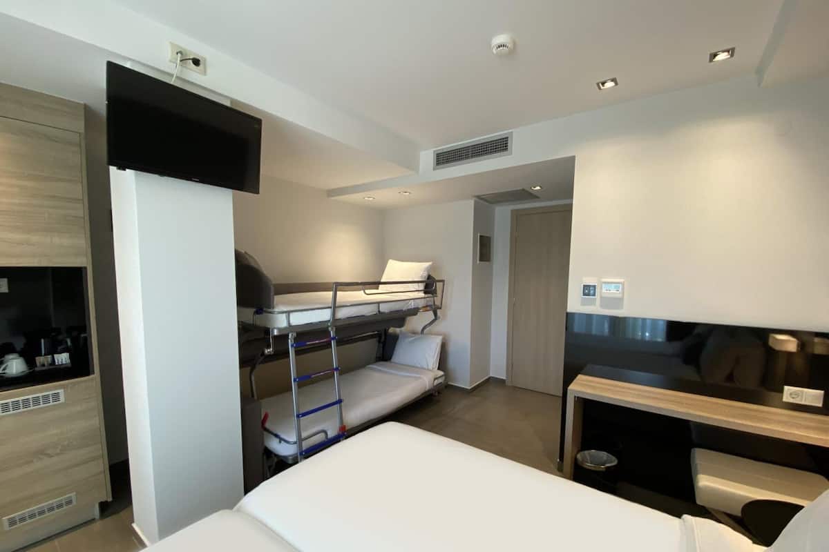 Een hotelkamer met stapelbedden, een bureau, een kledingkast en een kitchenette.