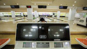 Une salle de bowling équipée de pistes Brunswick, d’un système de retour automatique des boules et d’un tableau d’affichage.