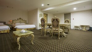Une chambre d’hôtel avec deux lits, une table à manger, des chaises décorées, une petite table et un miroir.