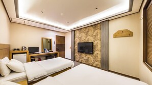 Une chambre d’hôtel avec deux lits, un bureau avec un ordinateur, une télévision et une petite kitchenette.