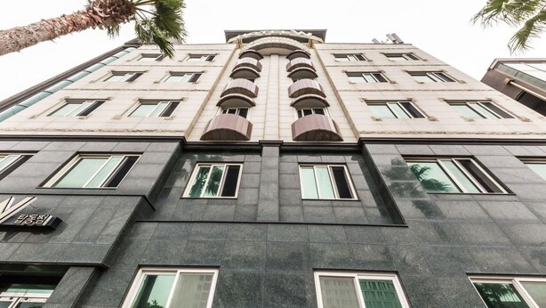 Un hôtel à plusieurs étages doté d’une architecture moderne, caractérisé par une arche centrale imposante et de nombreux balcons.