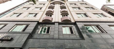 Un hotel de varios pisos con un diseño arquitectónico moderno, que destaca un arco central prominente y varios balcones.