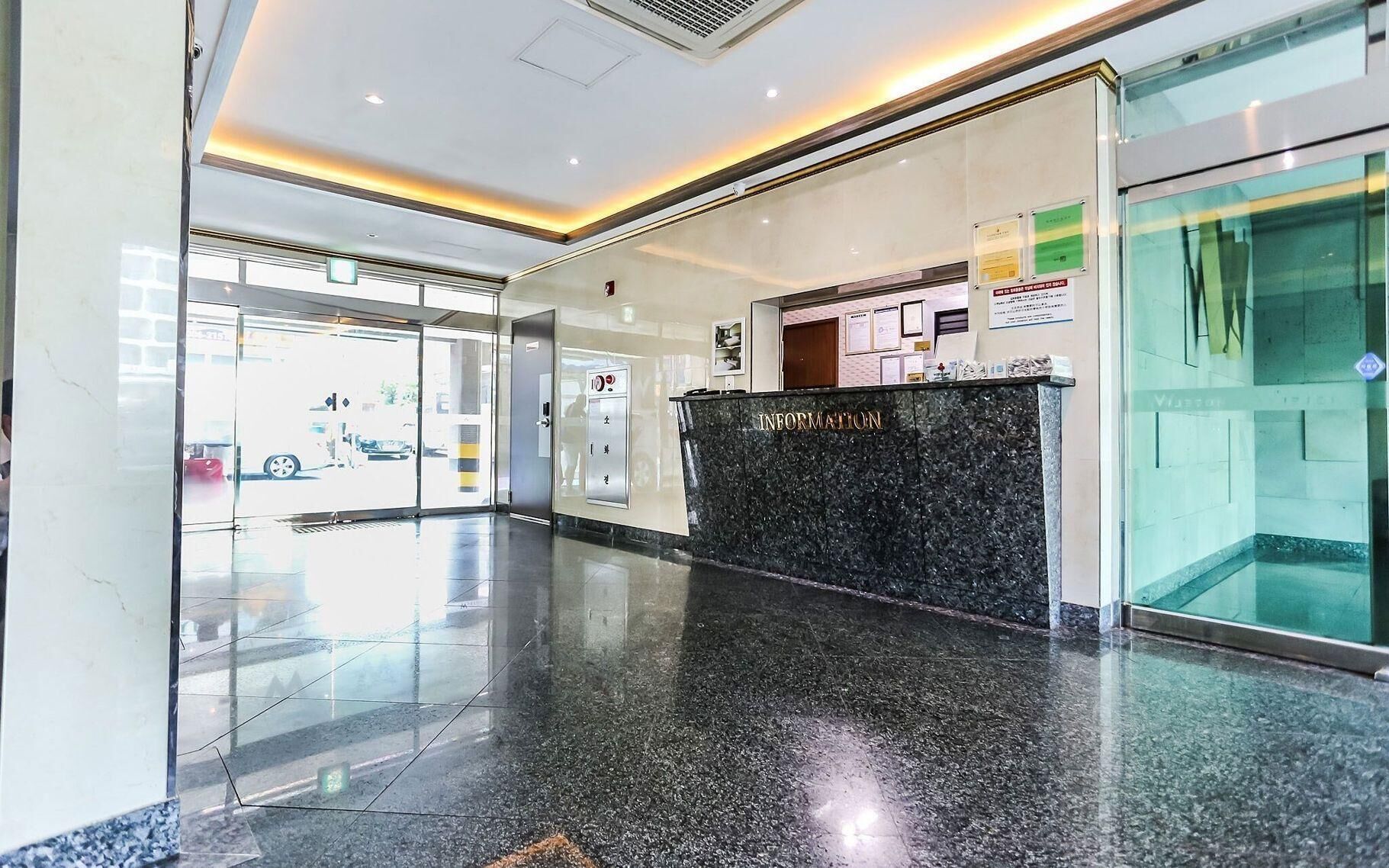 A reception area with a marble counter, glass doors, and a clear view of the parking lot outside.