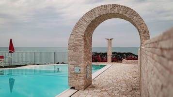 Piscina all'aperto, una piscina a sfioro, lettini