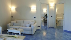 Una habitación de hotel moderna con un sofá blanco, una pequeña mesa y una cama.