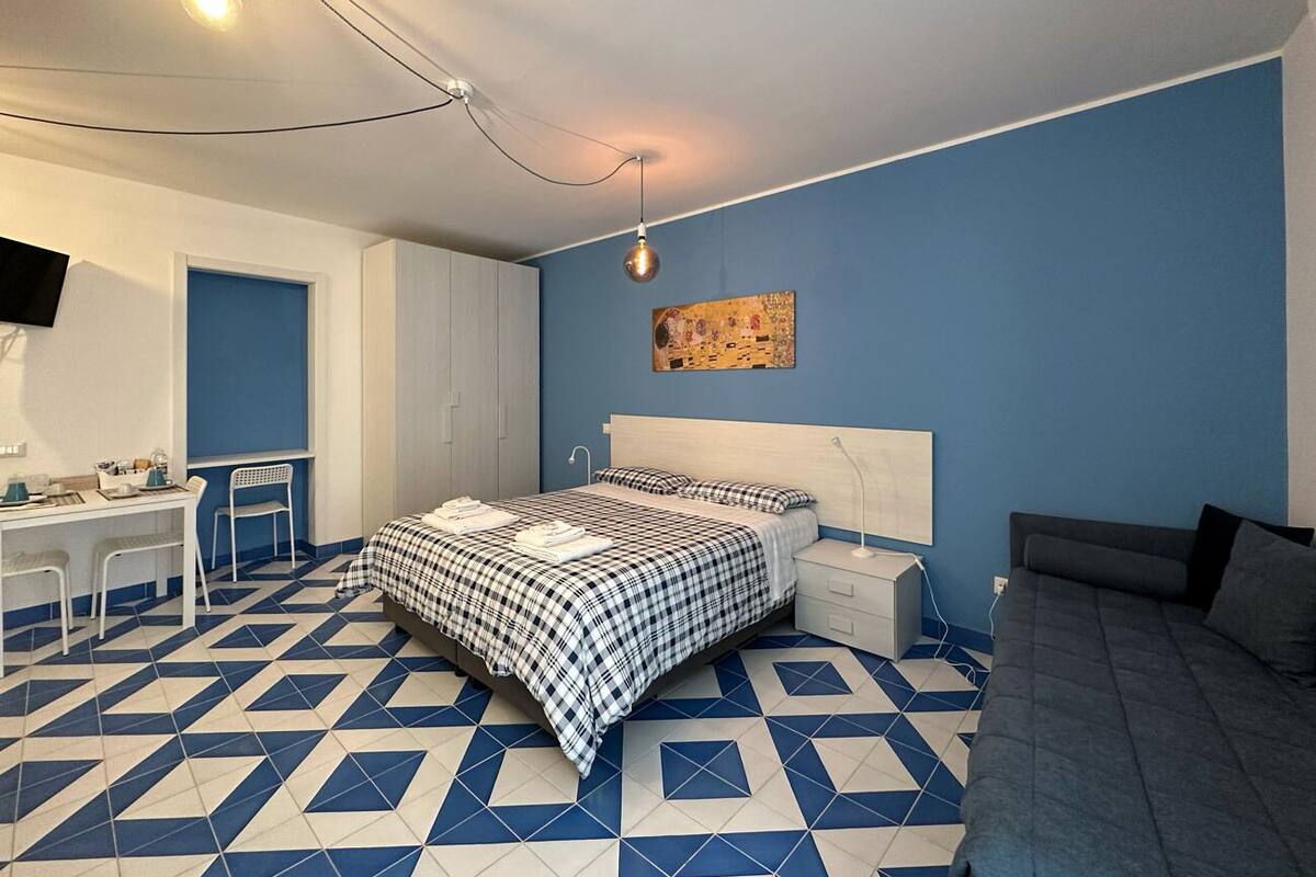 A bedroom with a bed, bedside table, and a desk with chairs.