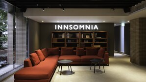 Un interno moderno con un divano componibile, due tavolini e una libreria con l'etichetta 'INNSOMNIA'.