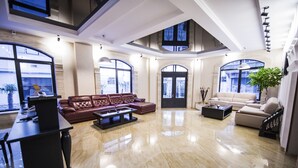 A spacious living room with a high ceiling, two sofas, a coffee table, and large windows offering views of the city. - Tbilisi Inn (Tbilisi)