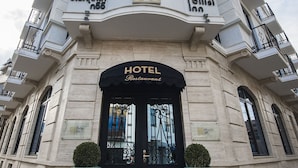 A hotel entrance with a black door, a sign reading "HOTEL Restaurant," and two potted plants on the steps. - Tbilisi Inn (Tbilisi)