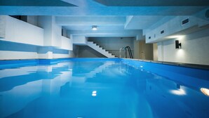 An indoor swimming pool with clear blue water, a ladder, and a staircase leading to an upper level. - Tbilisi Inn (Tbilisi)