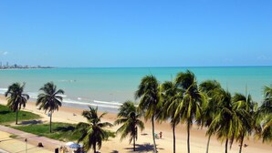 A beach with palm trees, a clear sky, and a calm sea. - Val Atlantic Hotel (João Pessoa)