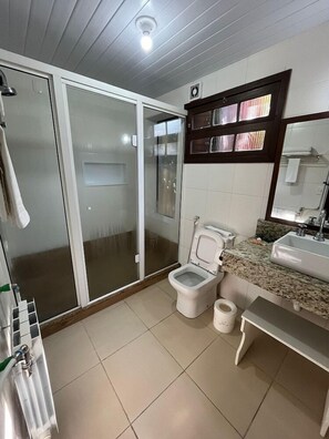 Un baño con inodoro, lavabo y cabina de ducha de vidrio.