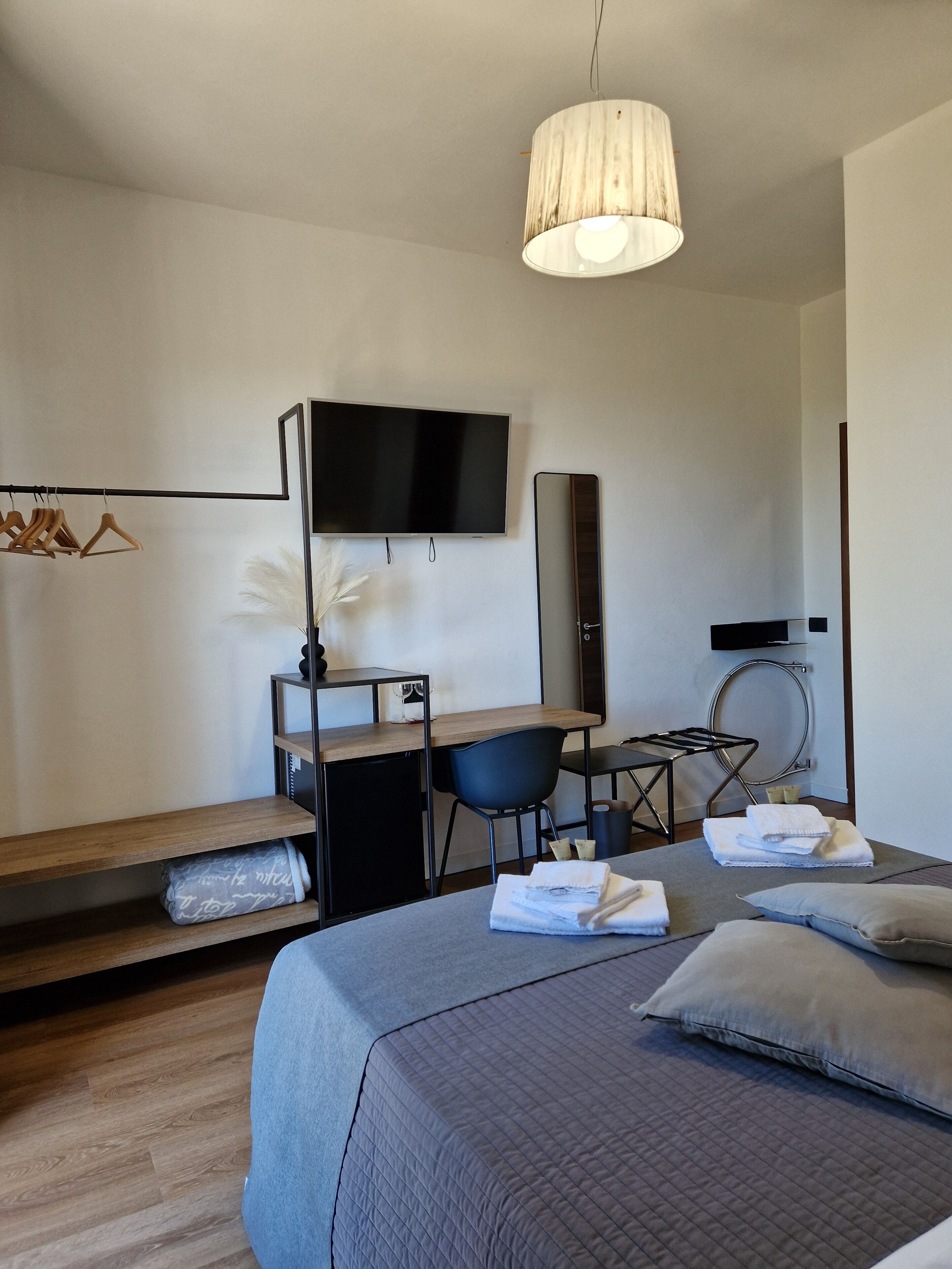 Ein modernes Hotelzimmer mit Bett, Schreibtisch, Stuhl, Fernseher und Spiegel.