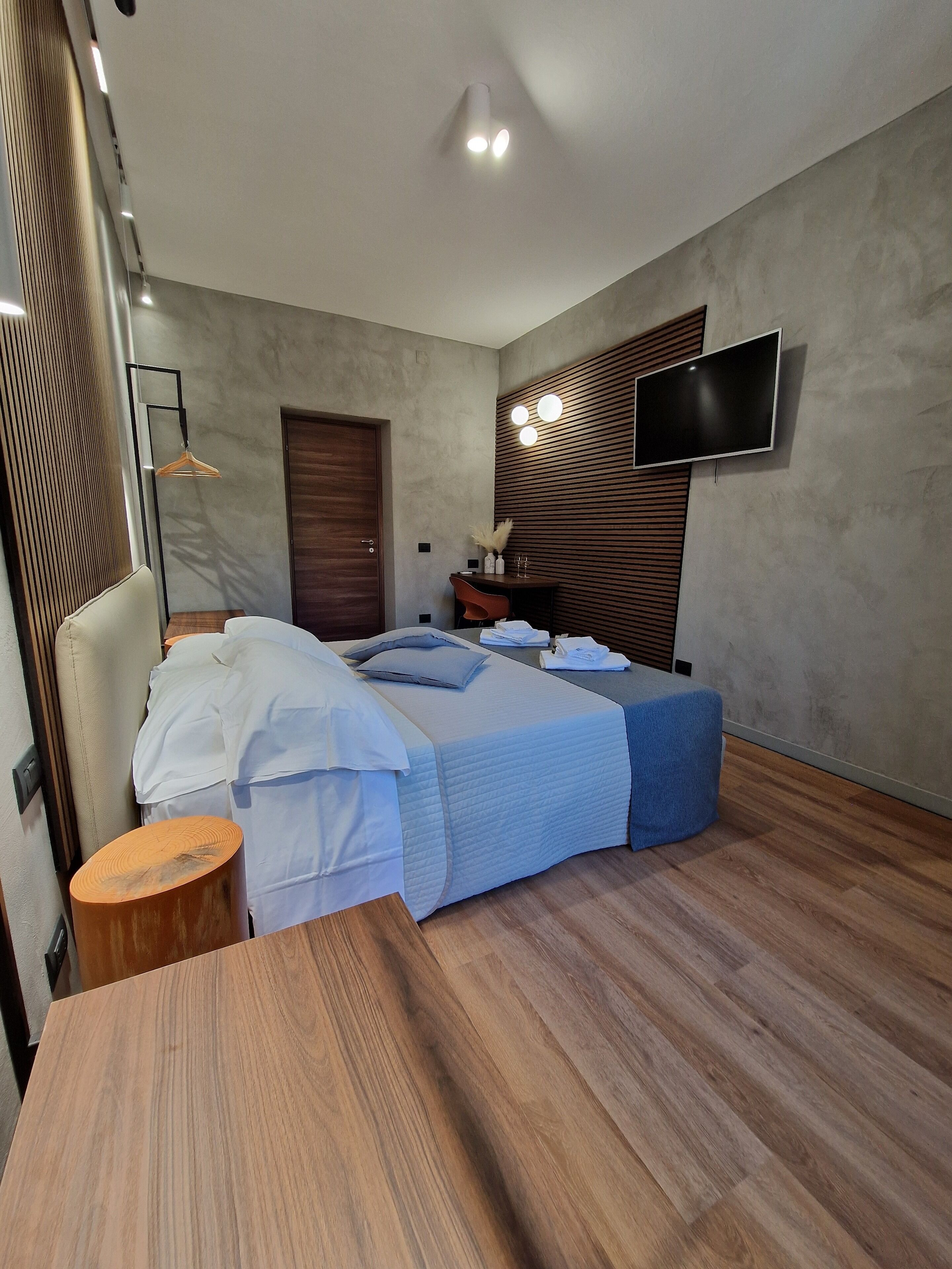 Une chambre à coucher moderne avec un lit, une table de chevet et un téléviseur fixé au mur.