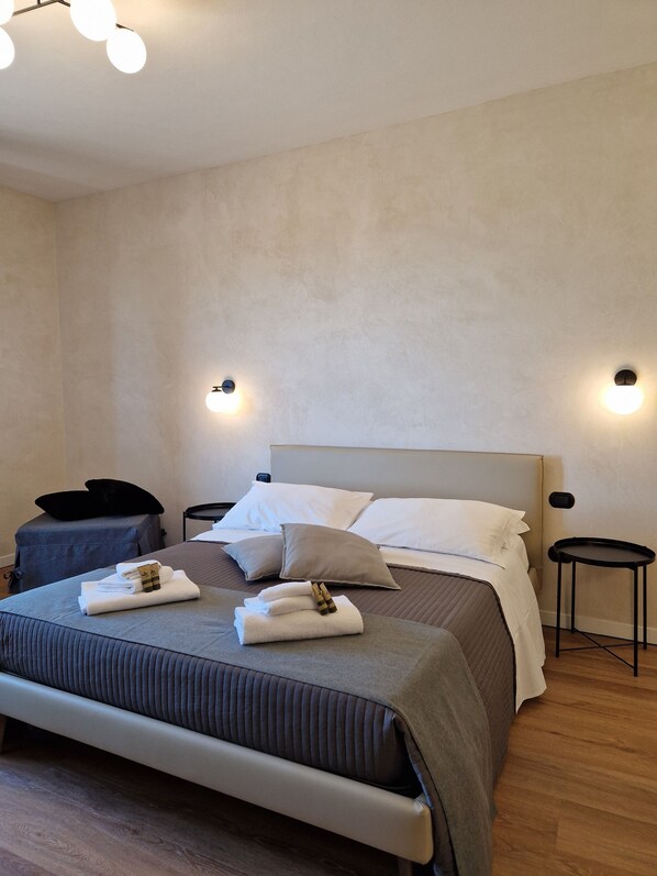 Une chambre à coucher moderne avec un grand lit, deux tables de chevet et une petite table d’appoint.