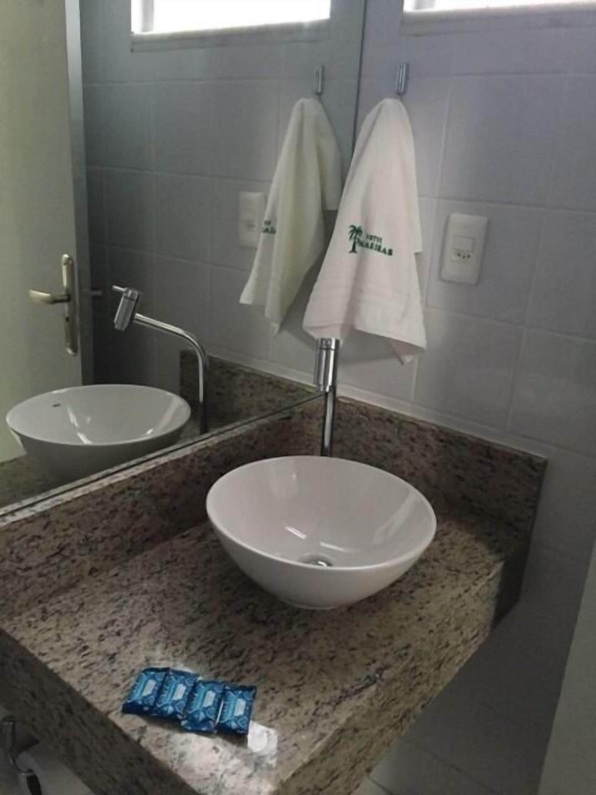 Un baño con dos lavamanos, un espejo y toallas colgadas en ganchos.