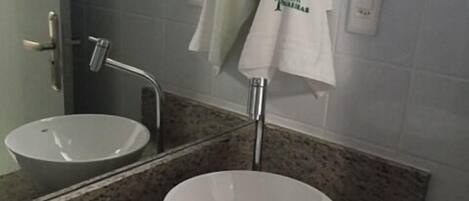 Un baño con dos lavamanos, un espejo y toallas colgadas en ganchos.