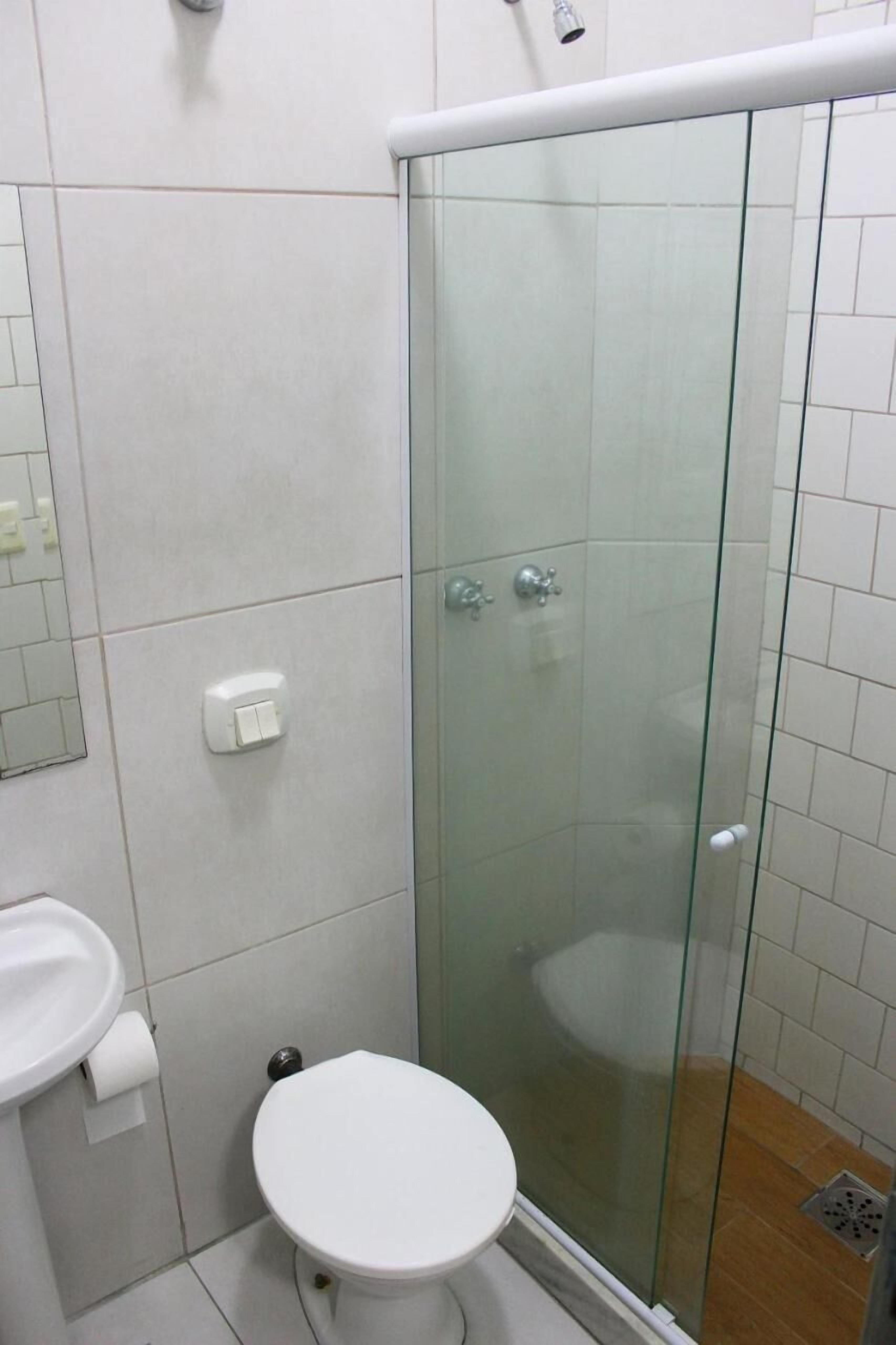 A bathroom with a glass-enclosed shower, a white toilet, and a sink with a mirror.