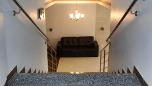 Una escalera conduce a una sala de estar con un sofá de cuero oscuro y una araña.