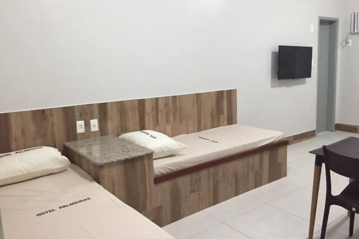 A hotel room with two beds, a wooden headboard, a flat-screen TV, and a small table.