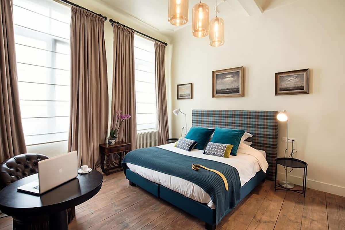Une chambre à coucher avec un lit, un ordinateur portable sur une table et une lampe.