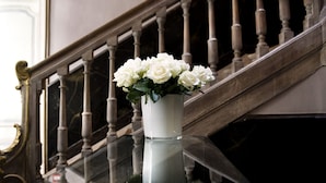 Uma escadaria com um vaso branco de flores brancas sobre uma superfície refletora.
