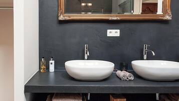 A modern bathroom with two white vessel sinks, a large mirror with an ornate frame, and a dark countertop.