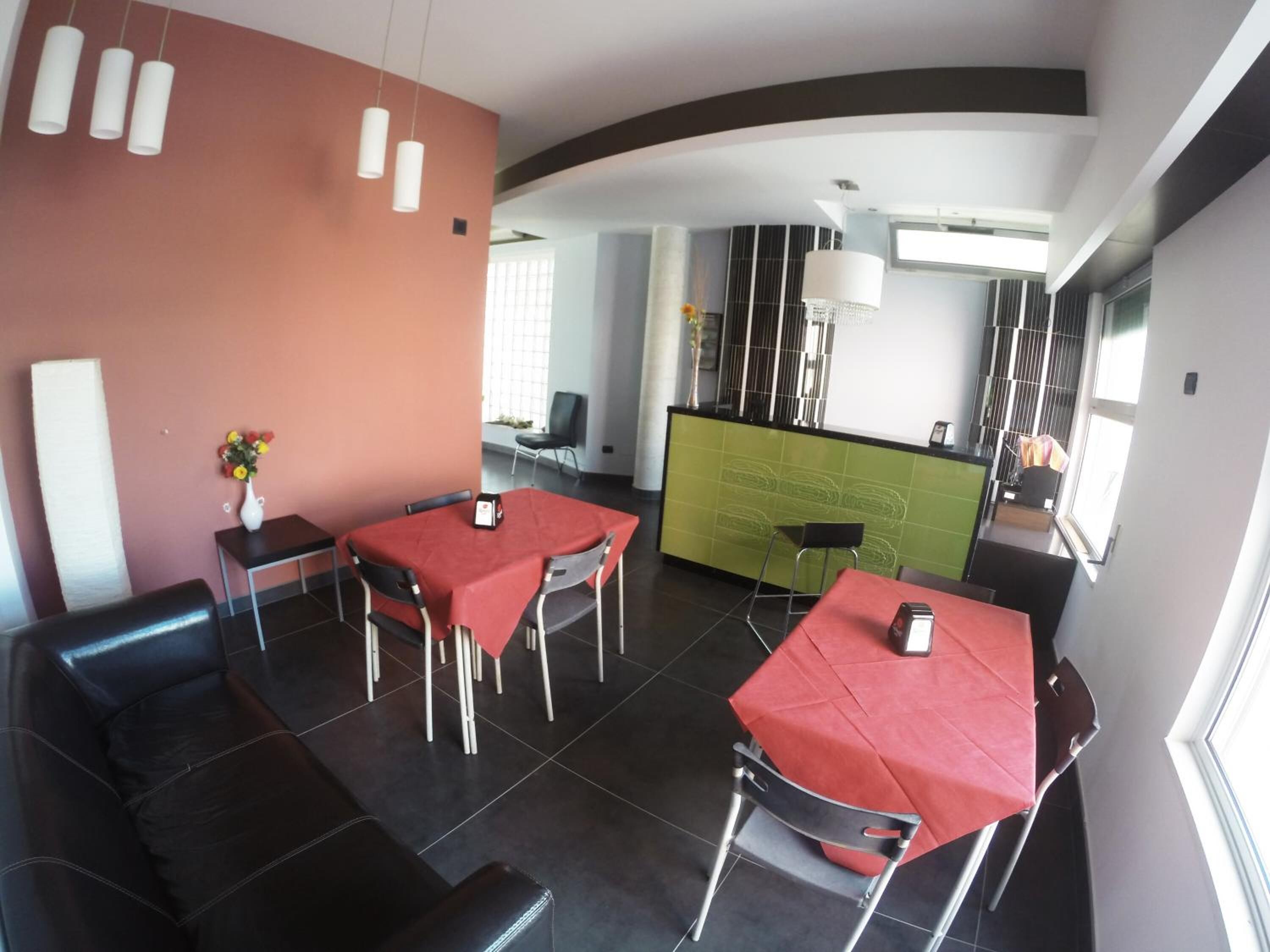 Un espace de restauration moderne avec des nappes rouges, des sièges en cuir noir et des luminaires suspendus.