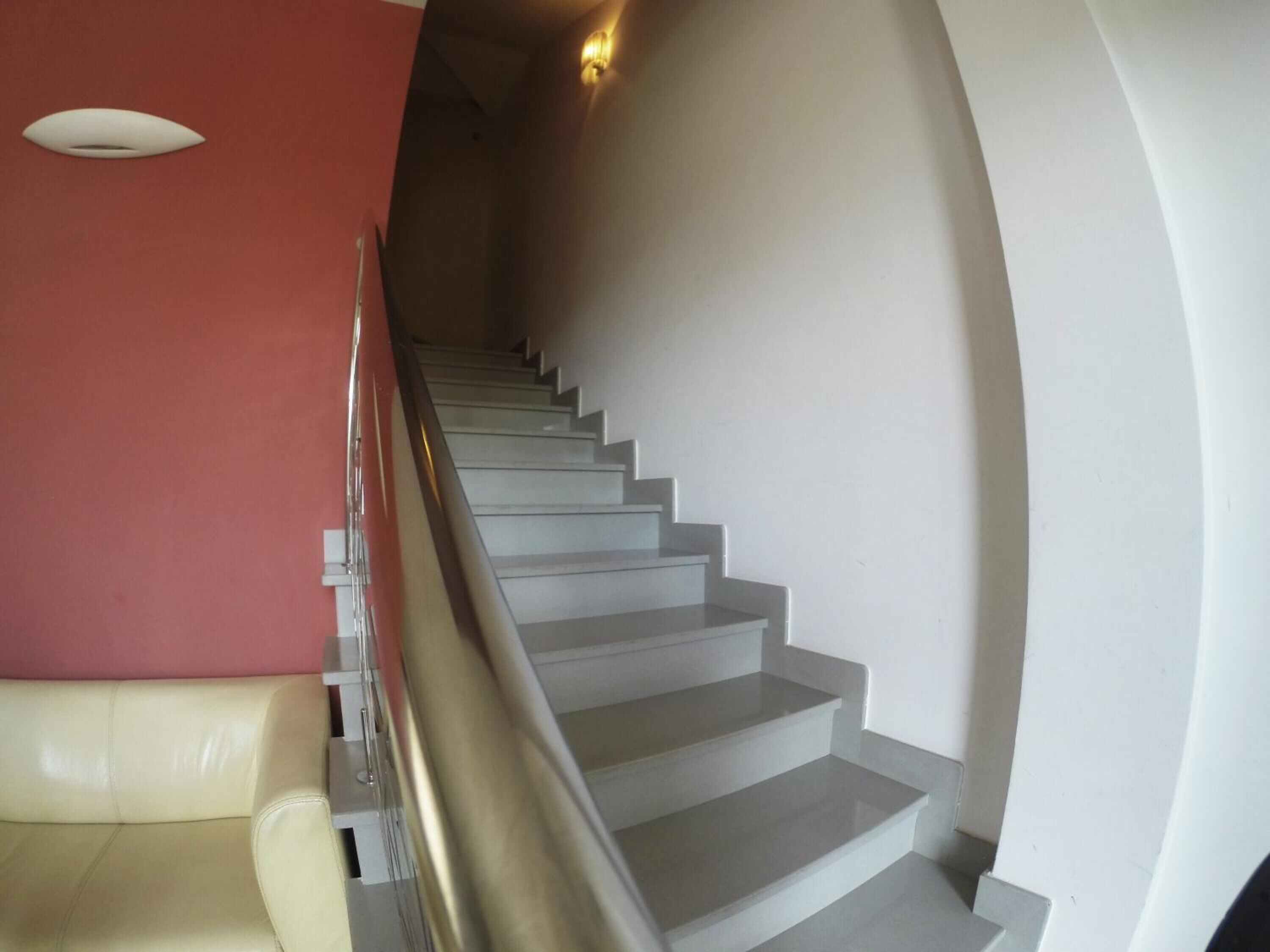 Eine Treppe mit Handlauf, einer roten Wand und einer weißen Wand.