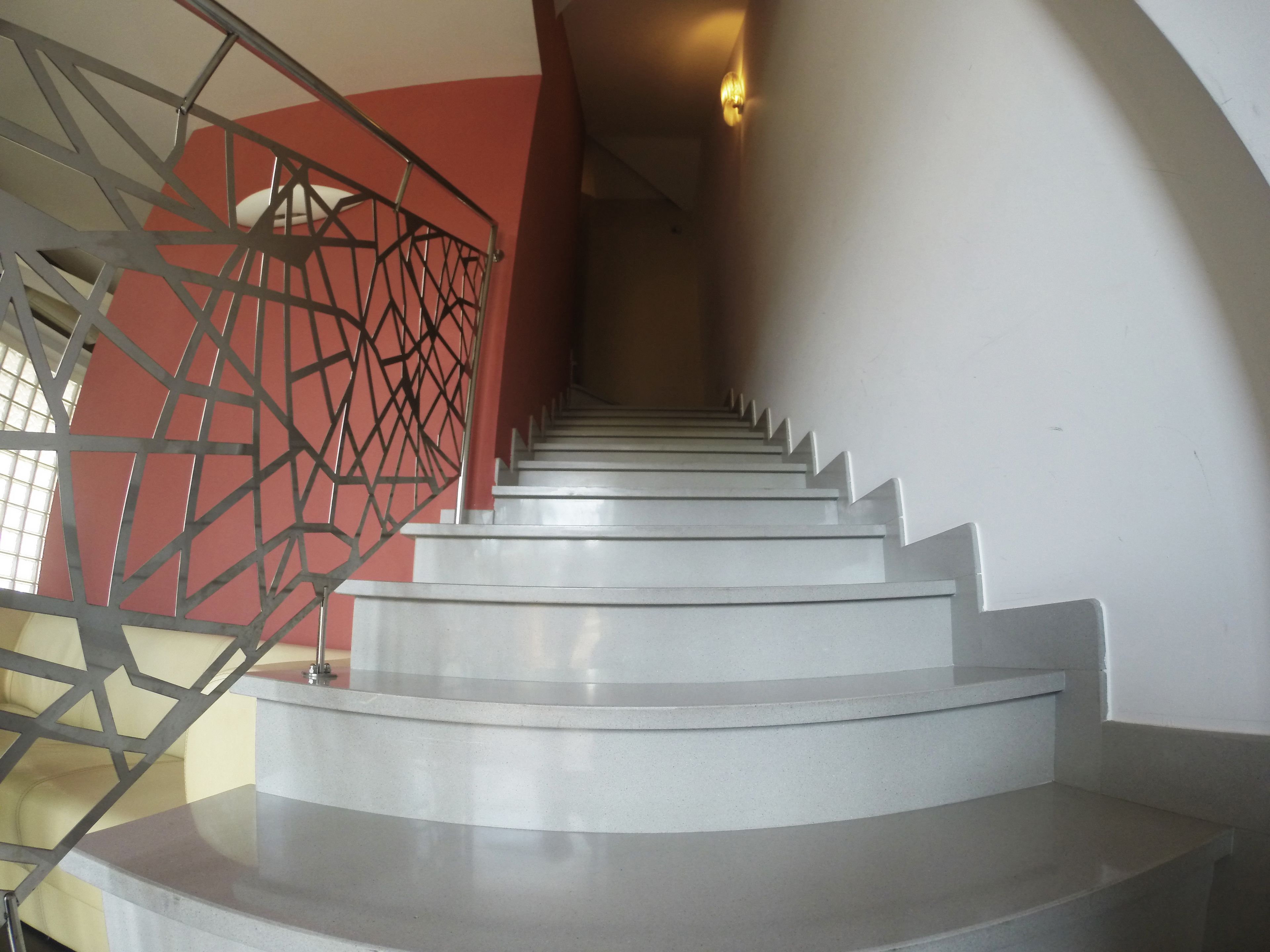 A staircase with a metal railing and a red wall on one side.