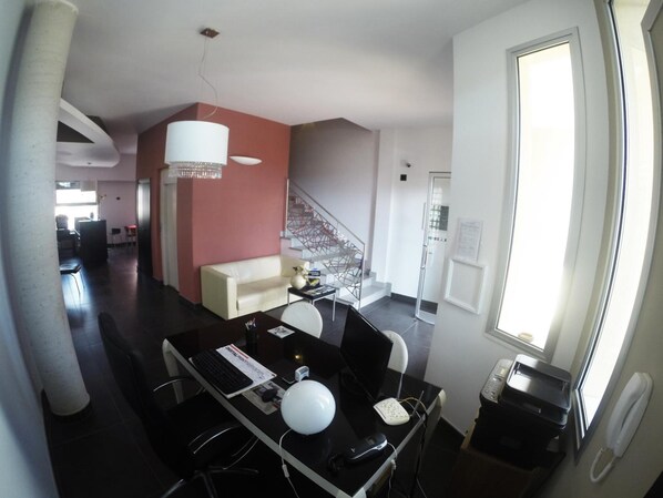 Una sala de estar moderna con un sofá, una mesa de comedor con sillas, una escalera y un ventanal grande.