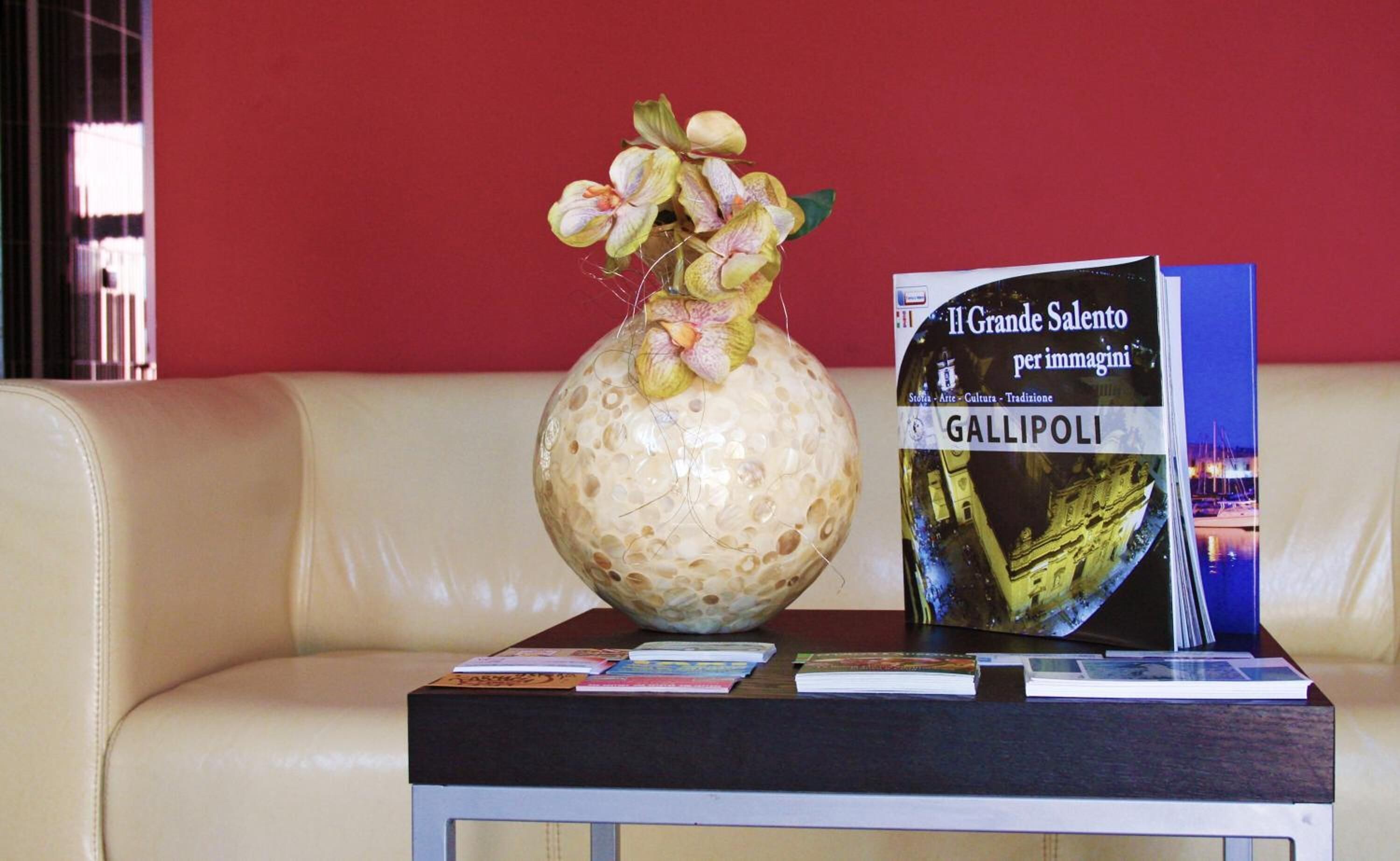 Un libro titulado 'Il Grande Salento per immaginini' sobre una mesa con un florero de flores.