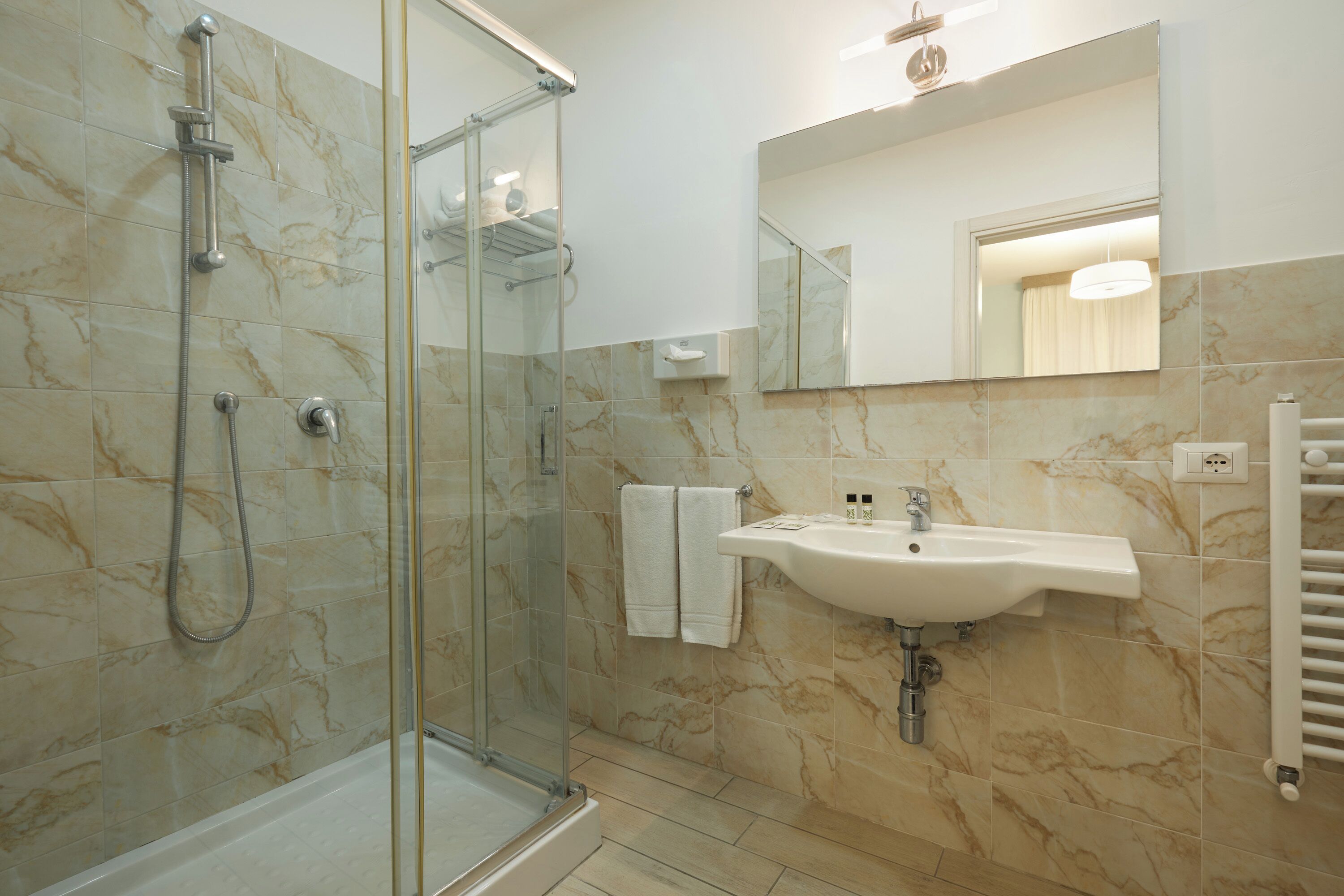 A modern bathroom with a glass-enclosed shower, a sink with a mirror above it, and a towel rack.