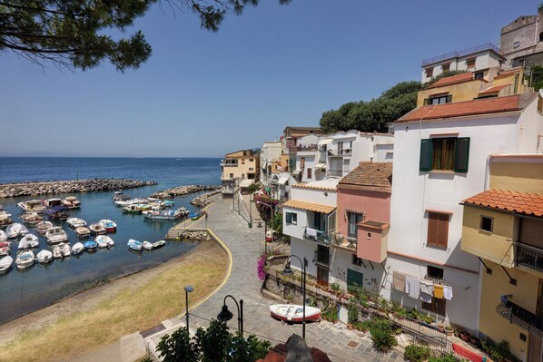 Un poble costaner amb edificis al front marítim, una marina plena de vaixells i una vista clara del mar.