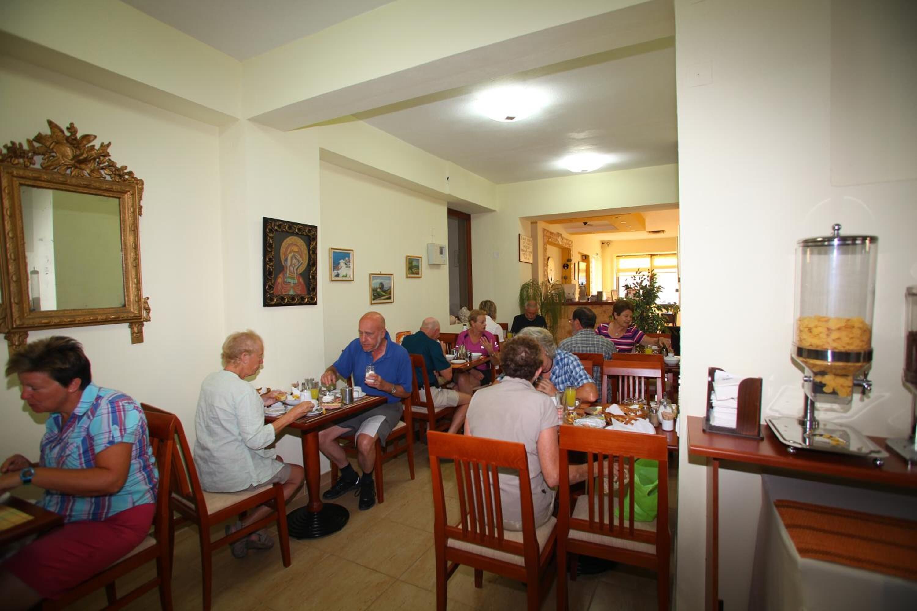 Un comedor con mesas y sillas de madera, una estación de buffet y cuadros en las paredes.