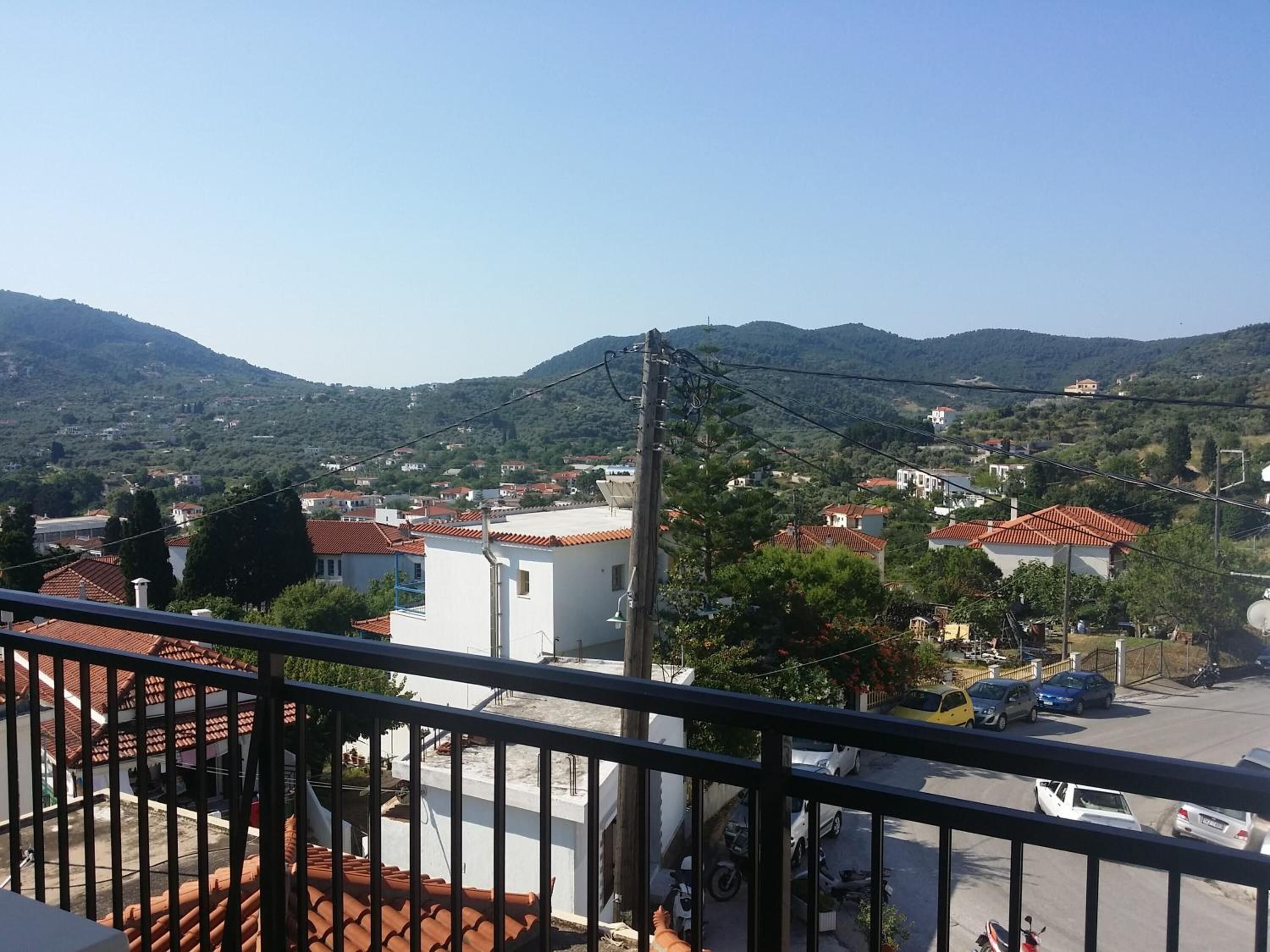 A residential area with houses, a clear sky, and a hilly landscape in the background.