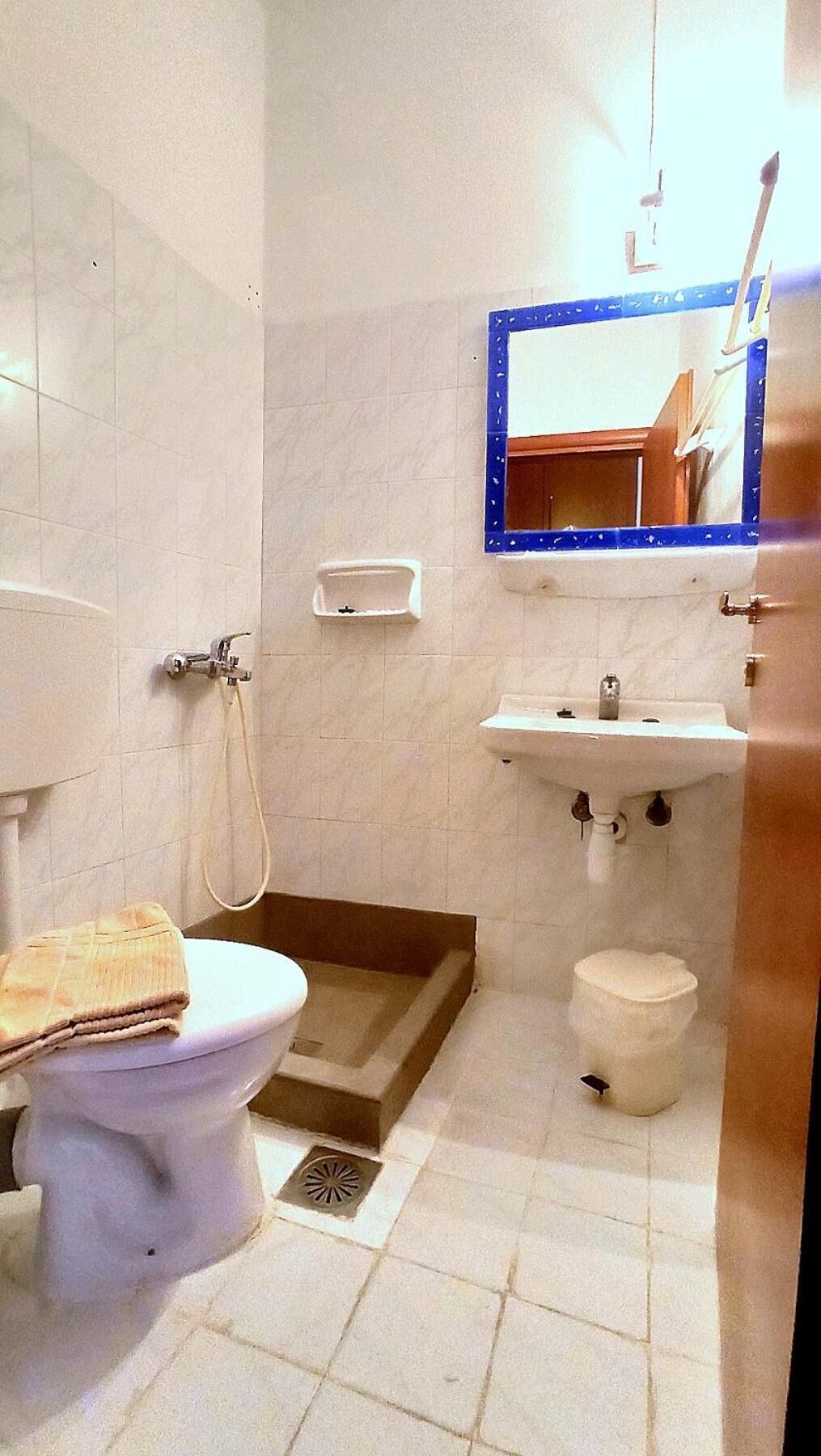 A bathroom with a toilet, bidet, sink, and mirror.