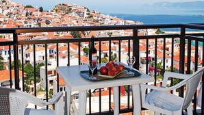 A balcony with a table set for two, overlooking a coastal town.