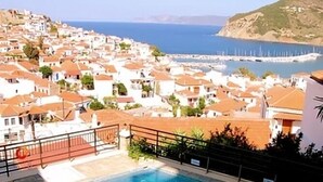 A swimming pool with a view of a coastal town and the sea.