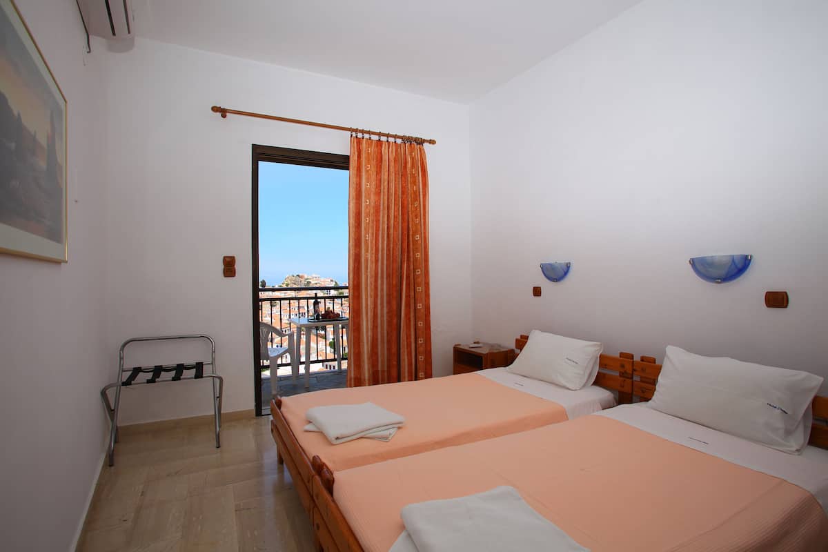 A hotel room with two beds, a balcony, and a view of the city.