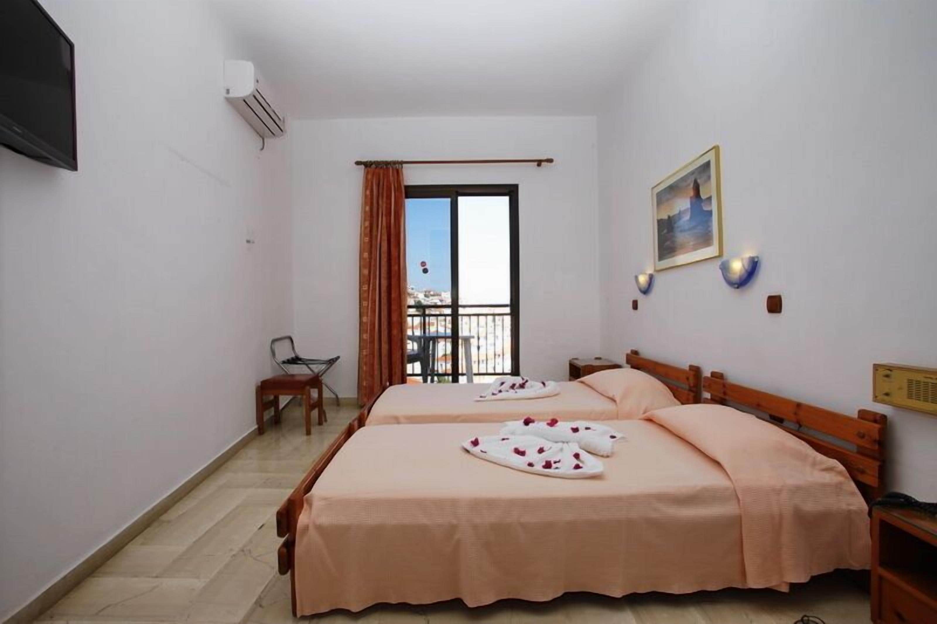 Une chambre d’hôtel avec deux lits, une télévision, la climatisation, un balcon avec vue et un tableau au mur.