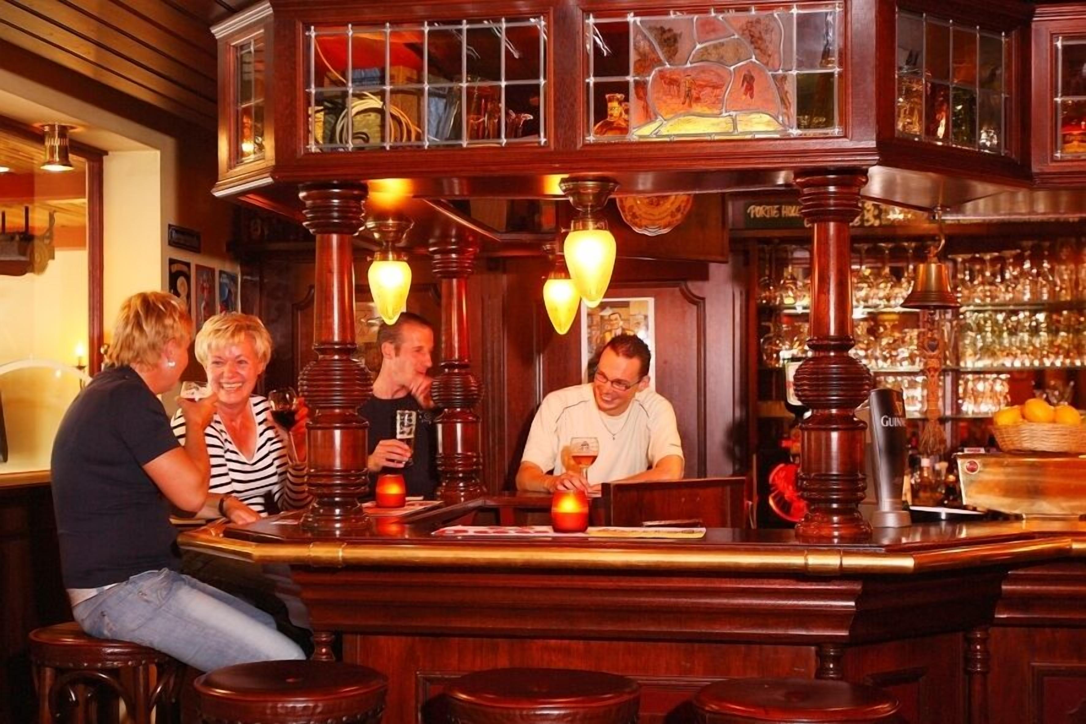Un bar con sgabelli in legno e un barista.