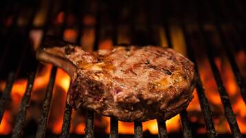 A steak grilling on a grill with visible flames.
